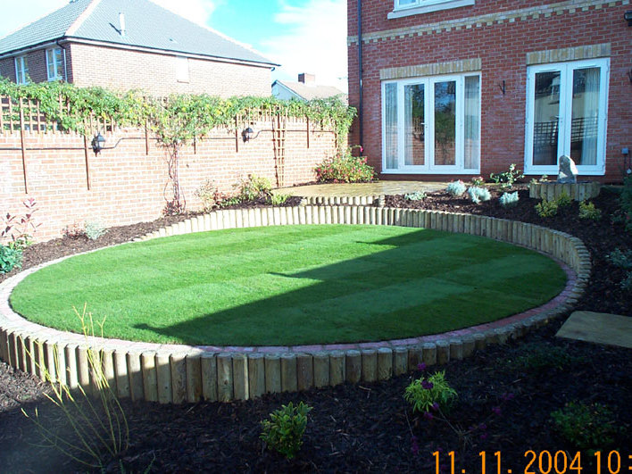 A gently sloping garden terraced to provide a level lawn area, new patio, water feature and planting