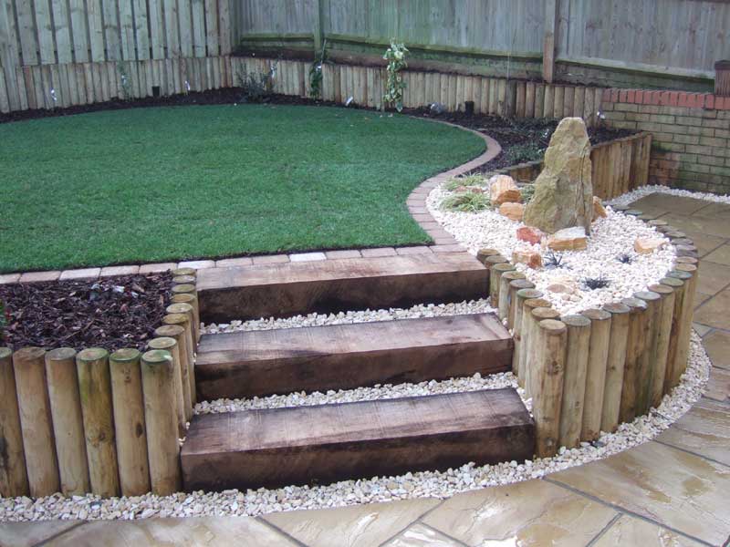 A sloping garden that has been terraced to provide a level lawn, patio planting areas and a water feature.