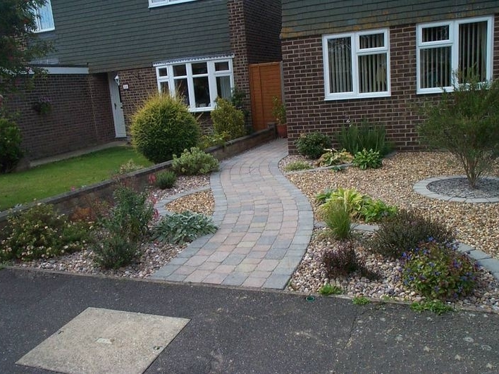A low maintenance front garden with a curved path and planting areas set amongst gravels.