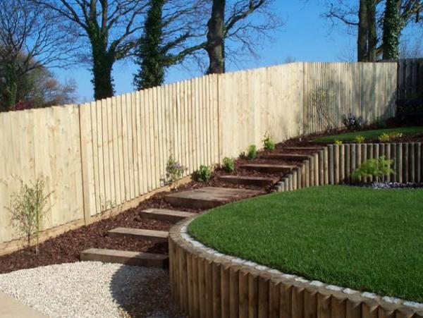 A sloping garden that has been terraced using timber to create an area of level lawn. Sleeper steps provide access to the higher level.