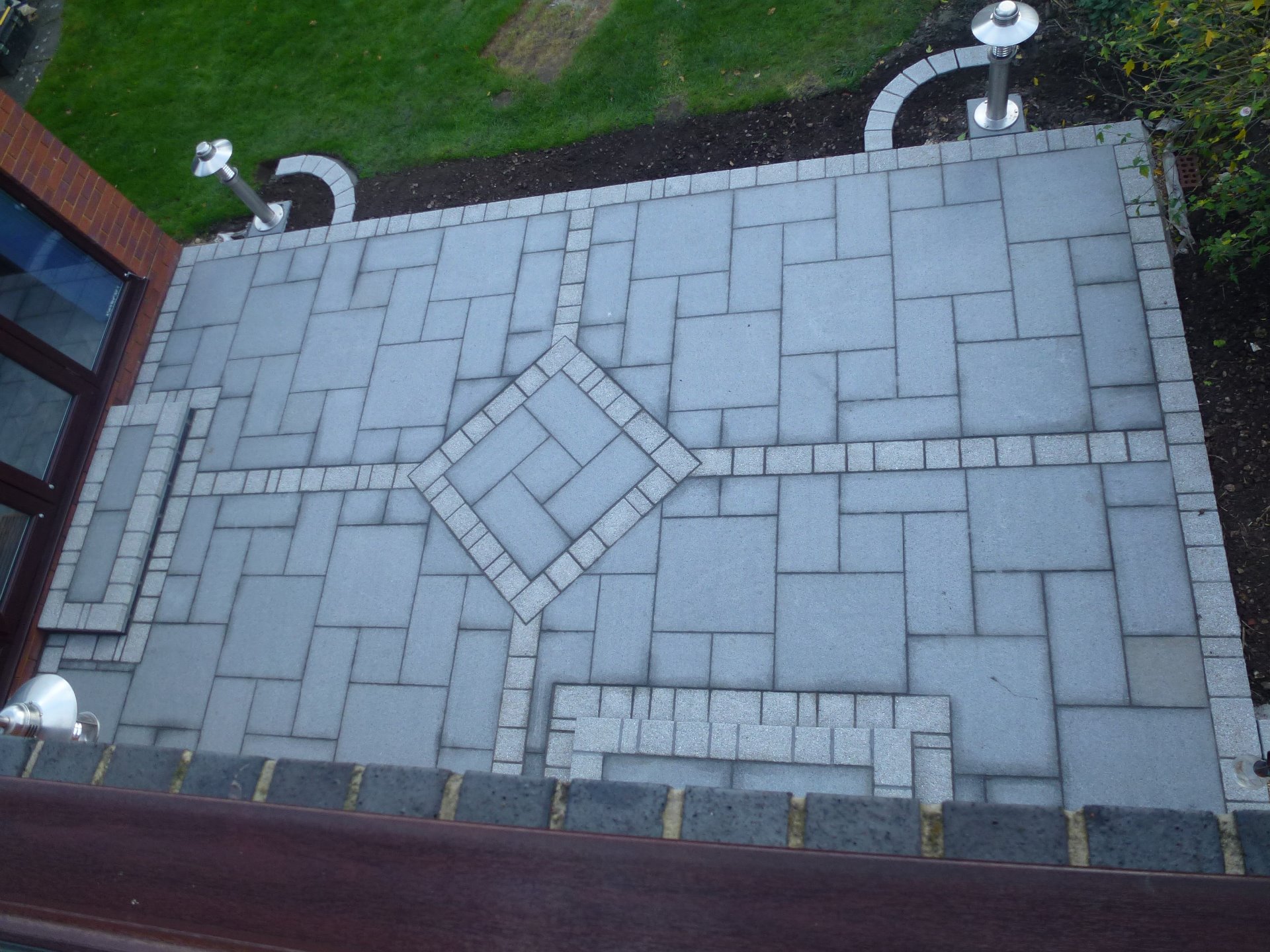 A patio laid with grey granite slabs, steps up to the patio doors, lighting, smooth paving
