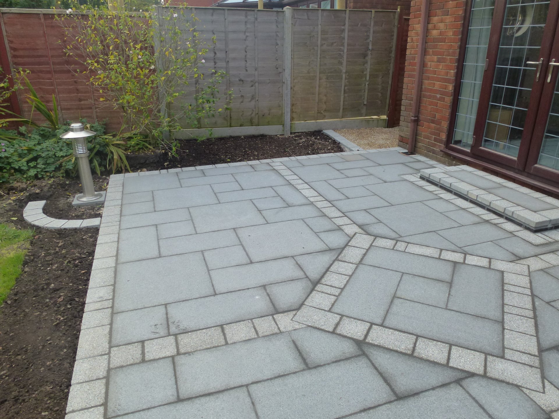 A new patio built with Chinese Granite paving slabs and Argent light paviours to add detail