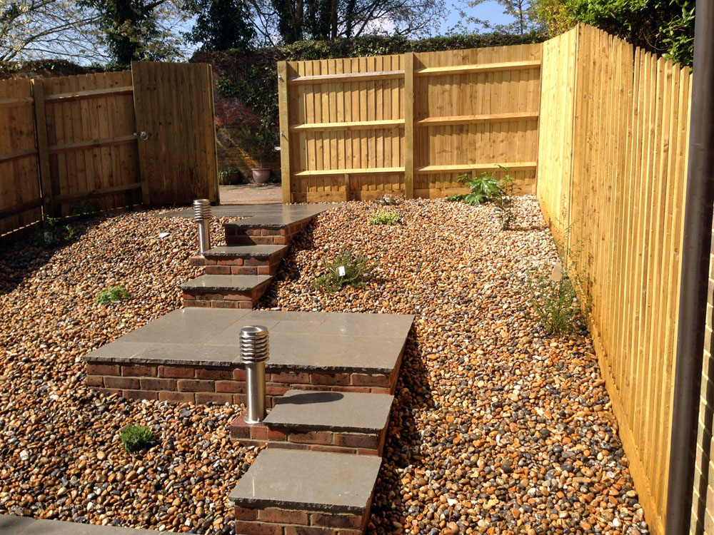 A complete garden makeover including fencing, patio, steps up to rear gate, lighting, planting and gravel for a low maintenance garden