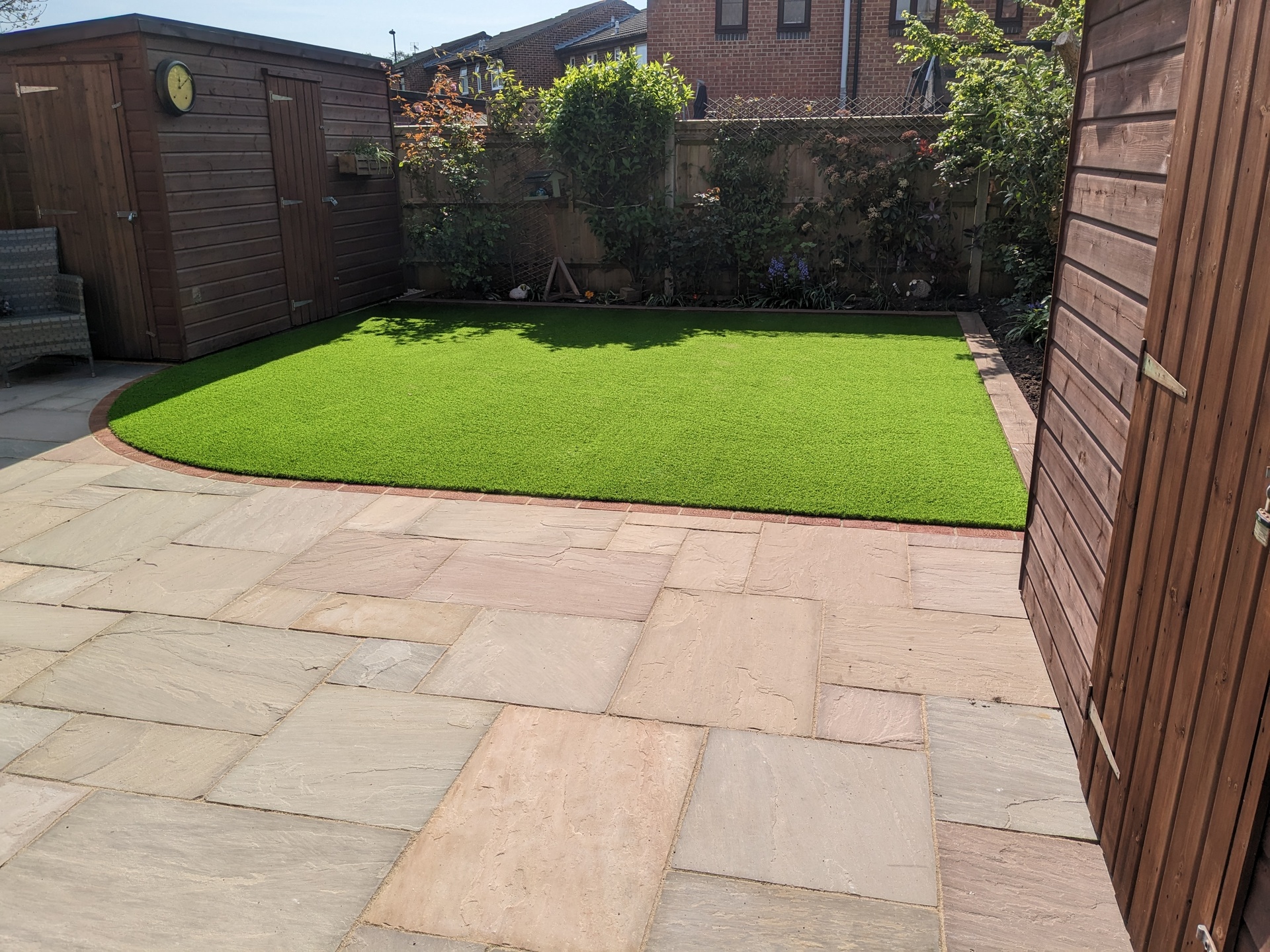 Back garden design and build with natural sandstone paving and artificial grass, sleepers and brick edging