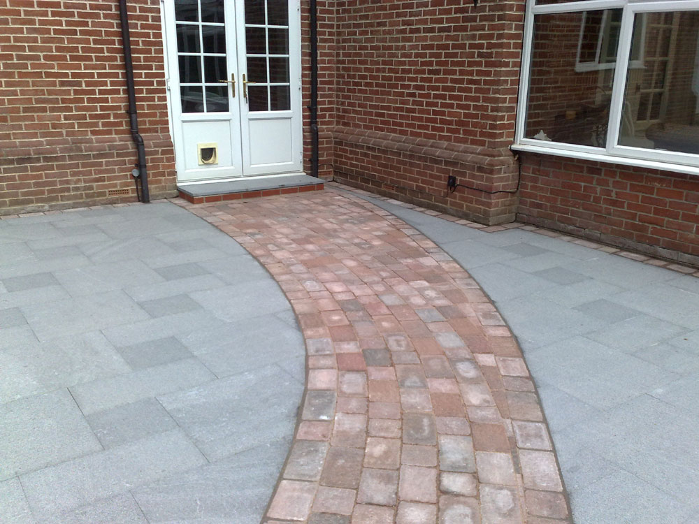 A new granite patio with a contrasting curver path leading to the rest of the garden.