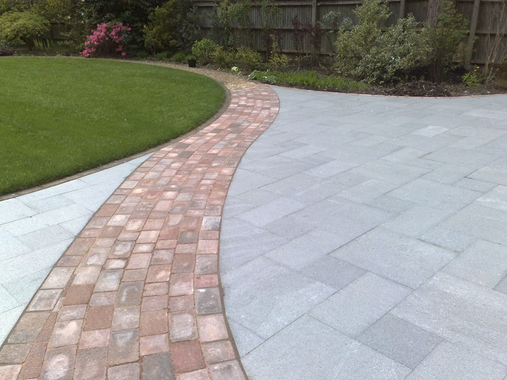 Another view of a curved path leading through a granit patio to the garden beyond.